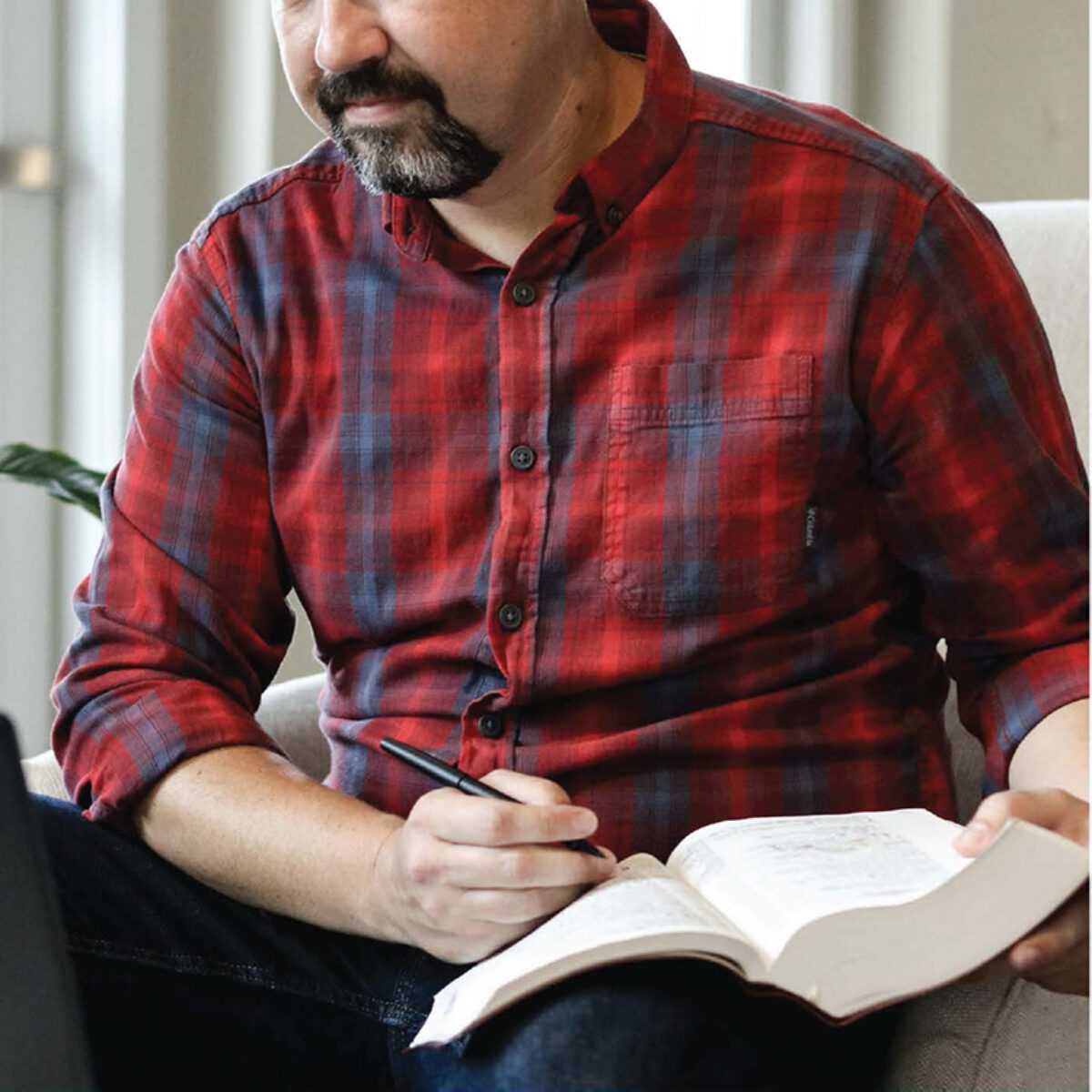 A man studies his Bible with a pen in hand