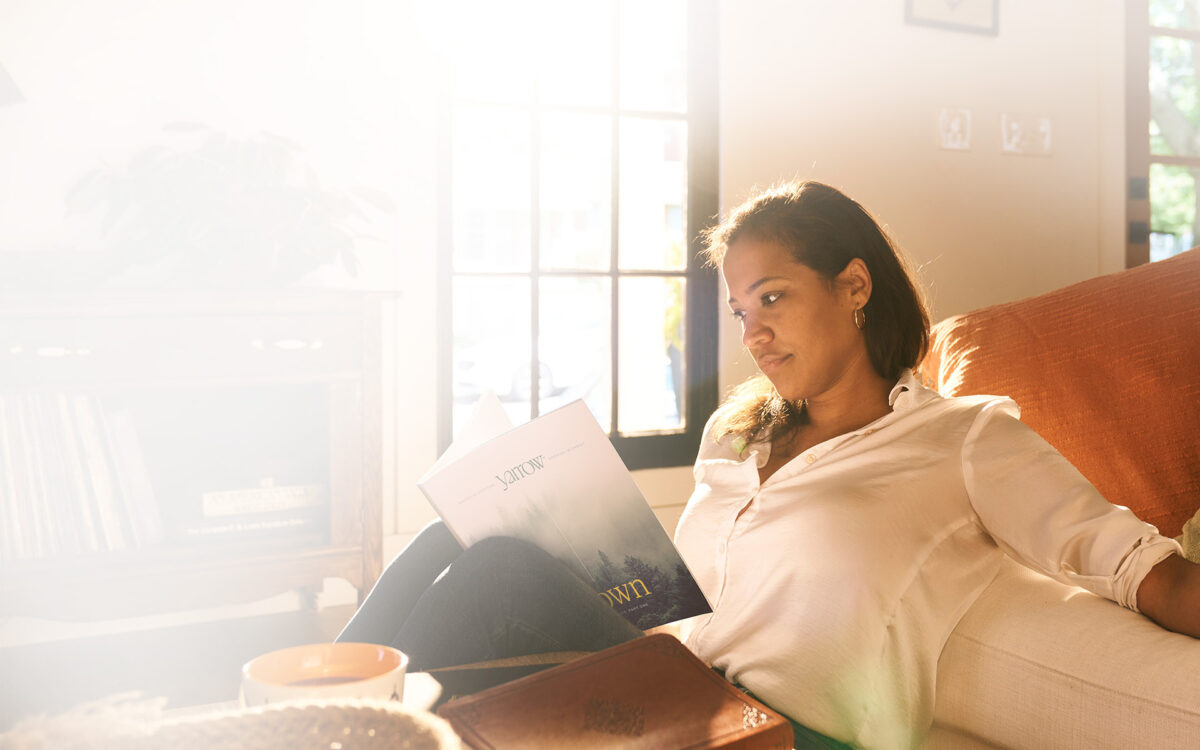 A woman reading a Yarrow Bible study with natural lighting