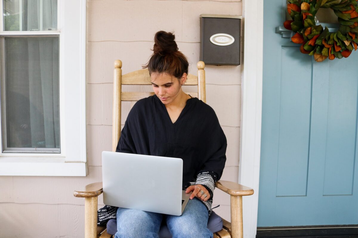 A woman using a laptop on the front porch to connect with Precept Bible study leaders from around the world