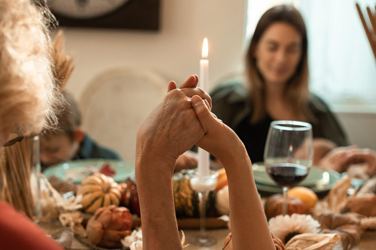 Two women holding hands during the Thanksgiving meal prayer